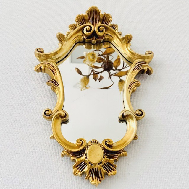 Prachtig barok vintage goud spiegeltje met een bijzondere vorm. De spiegel is rijkelijk versierd met ornamenten en is verguld met bladgoud. De brocante spiegel is 44 cm lang, en 29 cm breed.